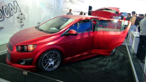1993 Ford Taurus - A red hatchback is displayed with its doors and trunk open, custom wheels and a unique paint finish.