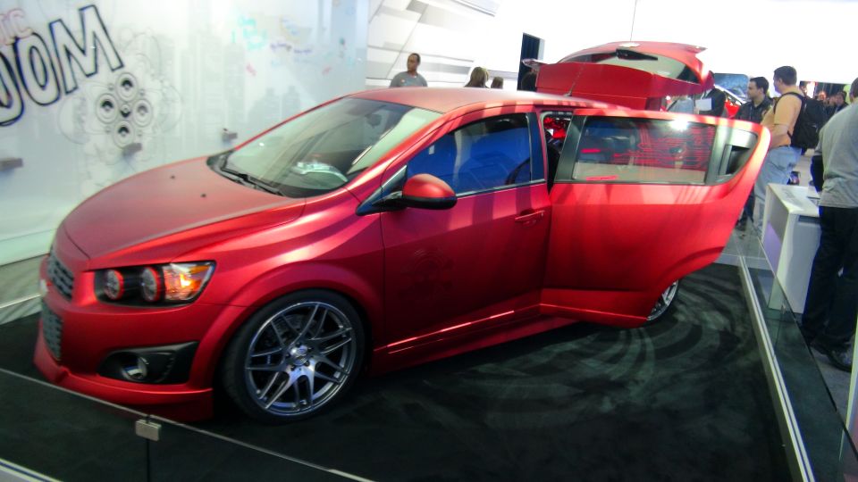 Red hatchback with doors and trunk open, custom wheels