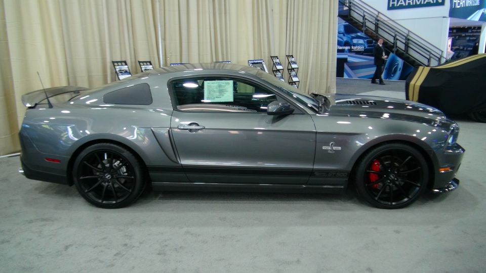 Gray Ford Mustang Shelby GT500 coupe with black racing stripes and red brake calipers