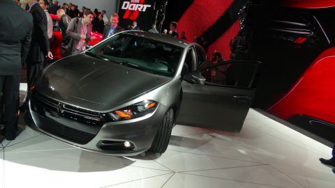 1993 Ford Taurus - A gray Dodge Dart is displayed with its door open at an auto show, with a red car visible in the background.