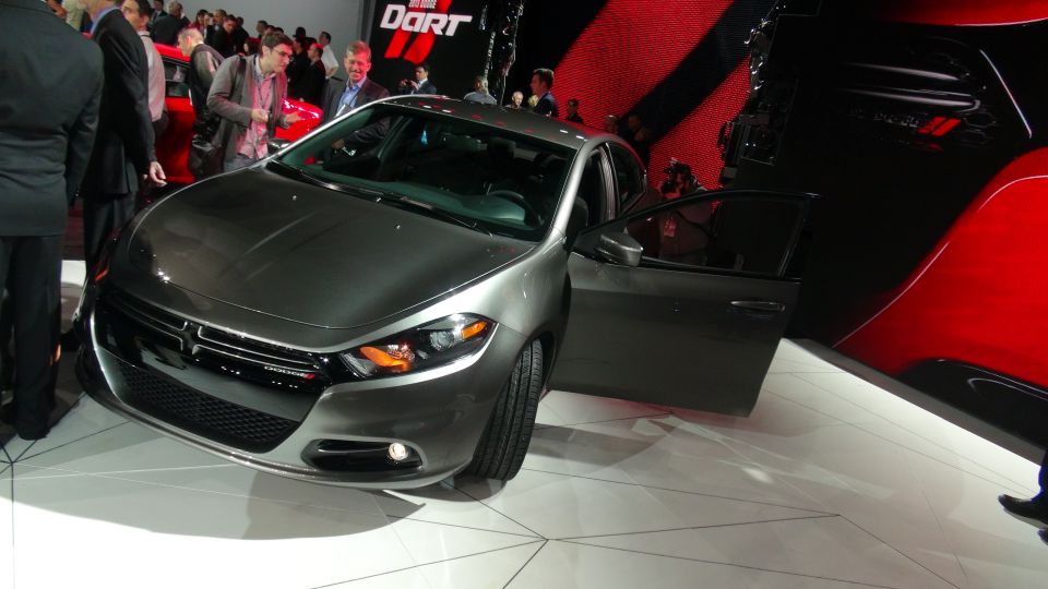 Gray Dodge Dart sedan with driver's door open, on display at an auto show