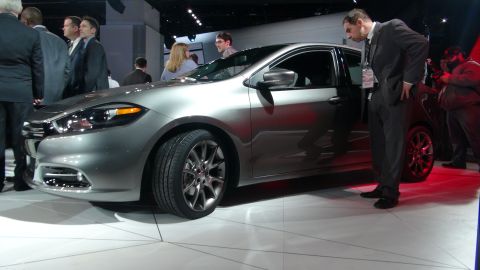 1993 Ford Taurus - A silver sedan is displayed at an auto show with its driver's door open and people looking at it.
