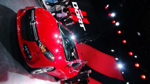 1993 Ford Taurus - A red 2013 Dodge Dart is displayed on a stage with a large banner in the background.
