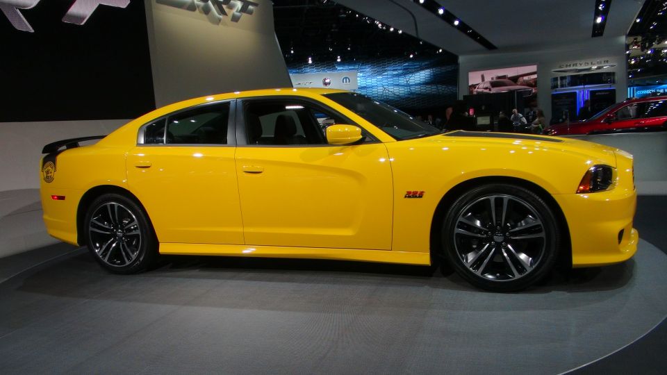 Yellow Dodge Charger with black spoiler and wheels, seen at an auto show