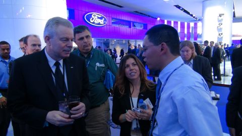 1993 Ford Taurus - Attendees converse at a Ford-sponsored event, with the company's logo visible in the background.