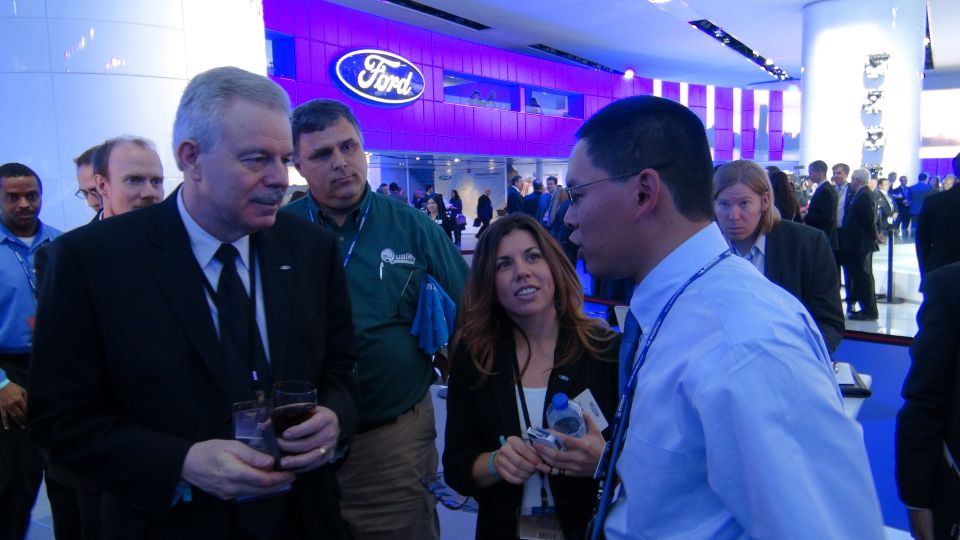 People gathered in front of a Ford logo at an indoor event