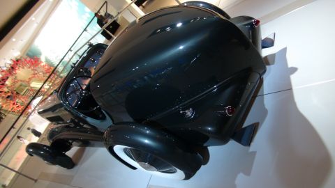 1993 Ford Taurus - A dark green vintage car with whitewall tires is displayed indoors.