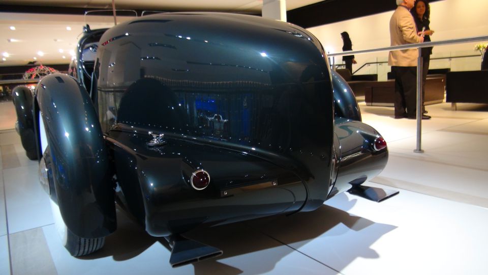 Dark green vintage car rear view with rounded fenders and dual exhaust pipes