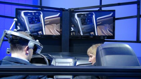 1993 Ford Taurus - People experience a virtual car interior at an auto show, with screens displaying the dashboard and cabin.