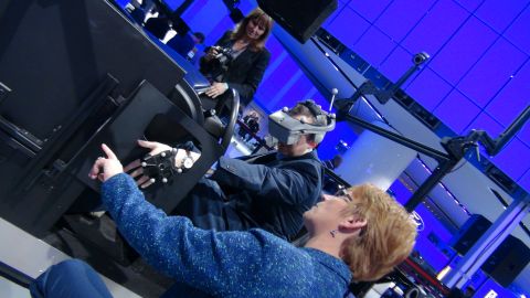 1993 Ford Taurus - Attendees experience a virtual reality driving simulator at an auto show.