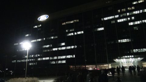 1993 Ford Taurus - The Ford Motor Company Headquarters building is shown at night, illuminated by interior lights and a prominent Ford logo.