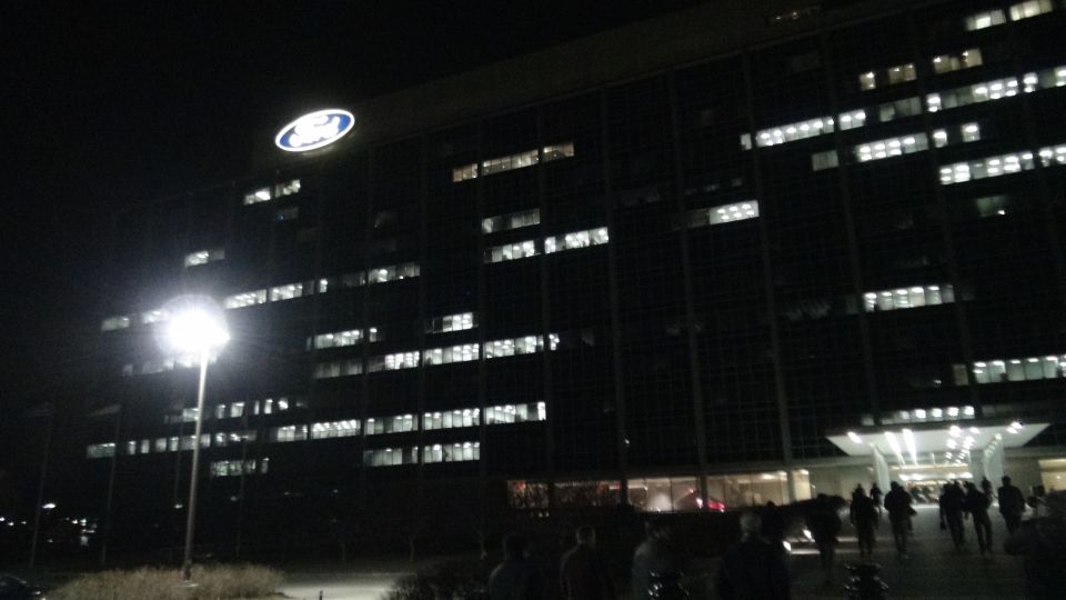 Ford Motor Company Headquarters building at night with illuminated windows and a large Ford logo on top