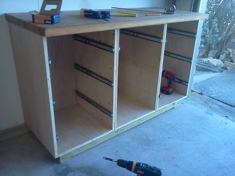 1996 Ford Bronco - A wooden workbench with drawer slides is shown, with tools and a drill on the concrete floor.