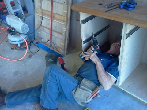 1996 Ford Bronco - A person is seen working on the interior of a cabinet, using a drill.