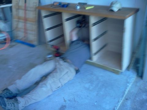 1996 Ford Bronco - A person is working on the interior of a cabinet, lying on the floor.