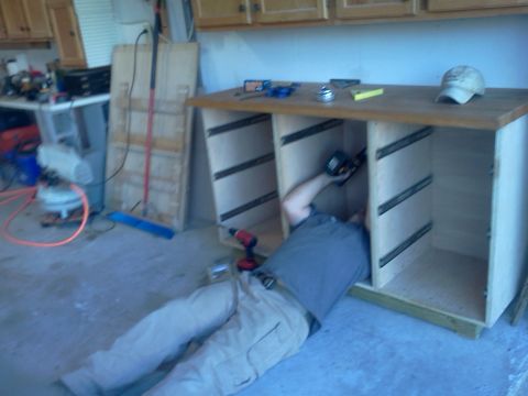 1996 Ford Bronco - A person works on assembling a cabinet in a garage setting, with tools scattered around.