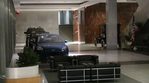 1993 Ford Taurus - A blue Ford Focus is parked indoors, alongside a vintage car and an American flag.