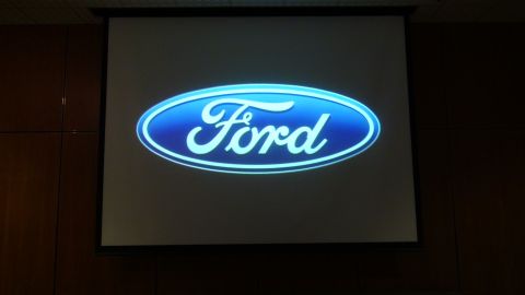 1993 Ford Taurus - The Ford logo is displayed on a projector screen in a room with wood-paneled walls.