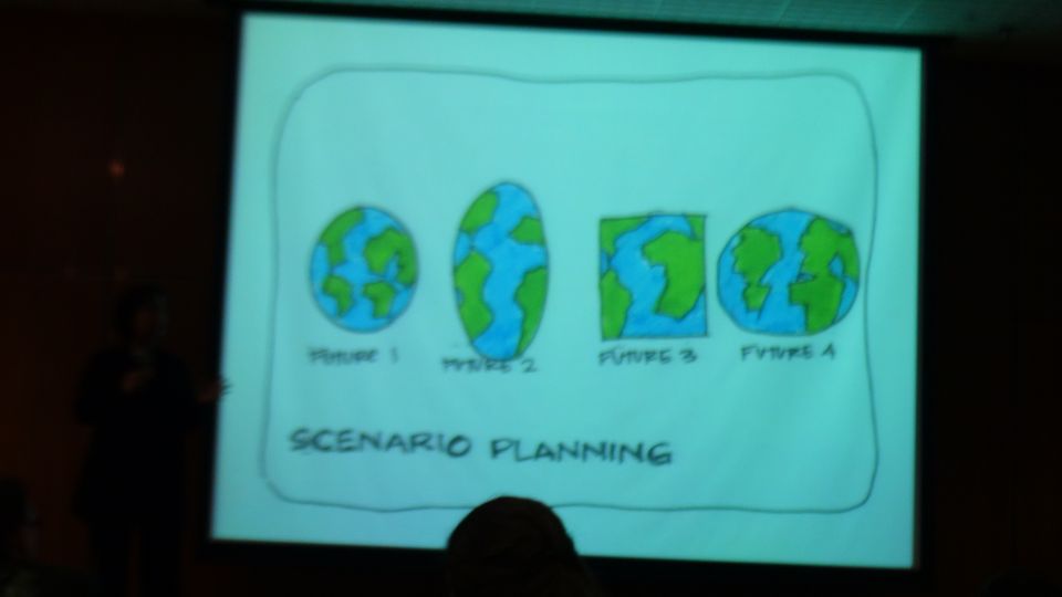 Photo of a projected presentation slide titled Scenario Planning with four hand-drawn Earths