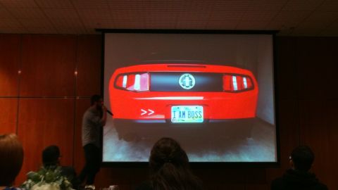 1993 Ford Taurus - The rear of a red car is displayed on a projector screen, a custom license plate.