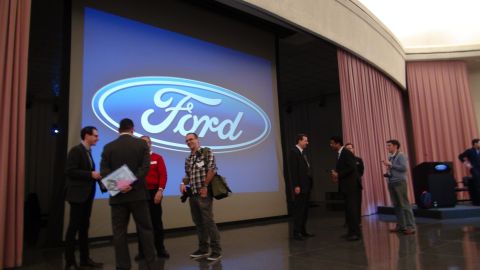 1993 Ford Taurus - An event features a prominent Ford logo displayed on a large screen with attendees present.