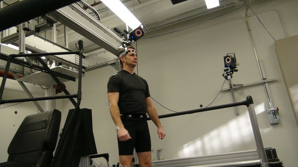 Man wearing motion capture sensors in a lab with cameras and equipment