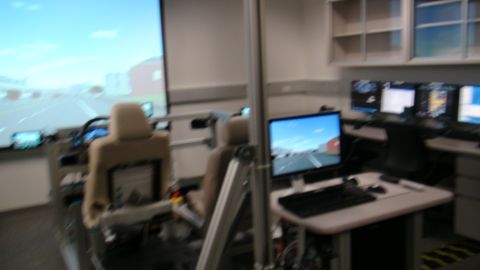 1993 Ford Taurus - A driving simulator setup features two seats and multiple monitors displaying a road simulation.