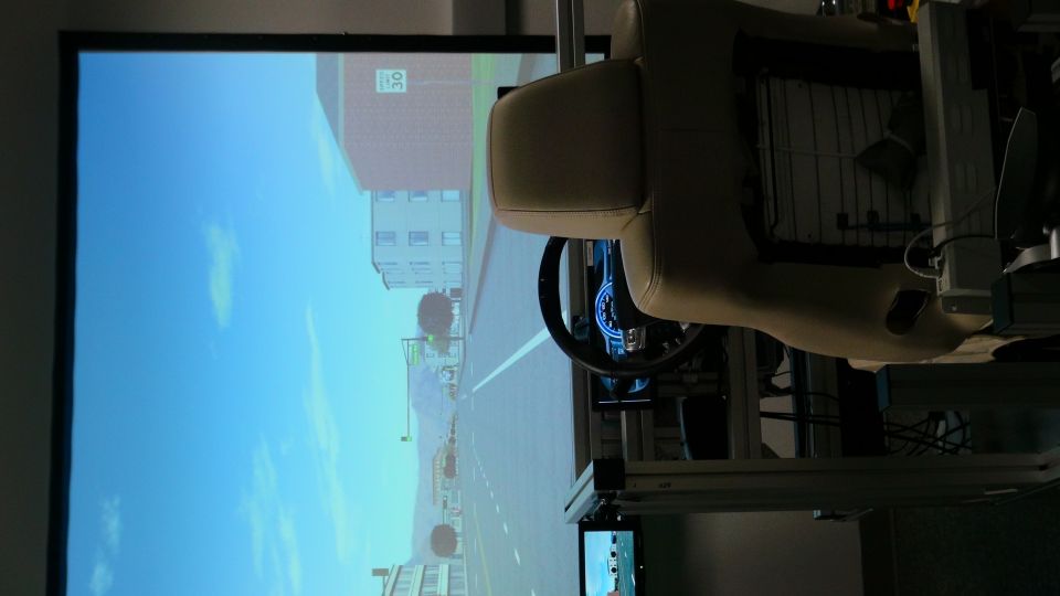 Car interior with steering wheel and projected road scene