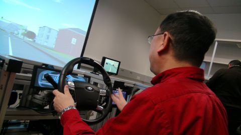 1993 Ford Taurus - A person operates a driving simulator, a Ford steering wheel and a projected road scene.