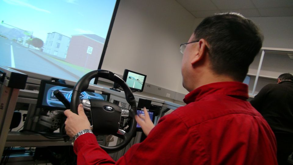 Person using a driving simulator with a Ford steering wheel and projected road