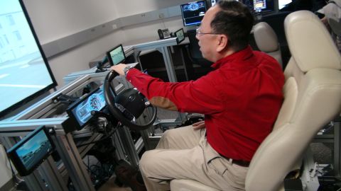 1993 Ford Taurus - A man operates a driving simulator, which features multiple screens displaying a road environment.