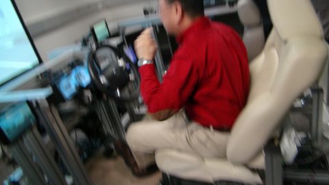 1993 Ford Taurus - A man operates a car simulator, his hands gripping the steering wheel.