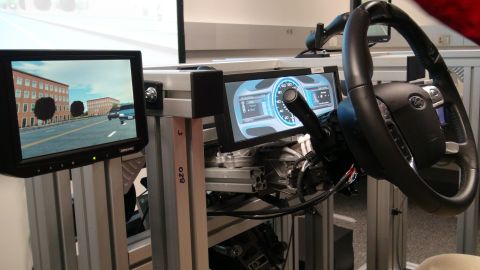 1993 Ford Taurus - A car interior simulator features a steering wheel and two screens displaying a virtual street and dashboard gauges.