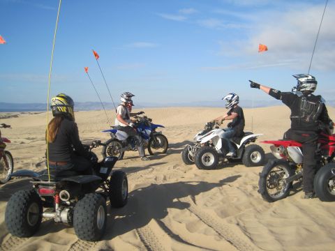 1968 Ford Bronco - A group of riders on dirt bikes and ATVs enjoy a day in the sand dunes under a clear blue sky.