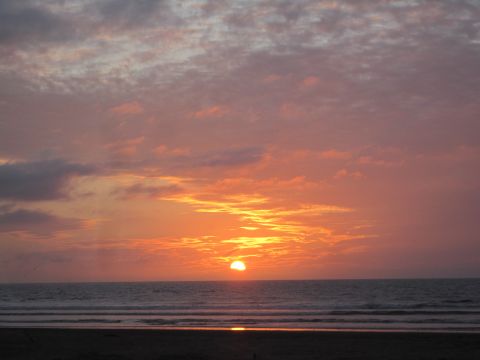 1968 Ford Bronco - A colorful sunset paints the sky over the ocean, with waves gently lapping the shore and a watermark visible.