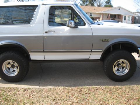 1994 Ford Bronco - Side profile of a two-tone white and grey 1994 Ford Bronco, showing its distinctive body style and wheels.