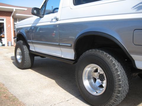 1994 Ford Bronco - Side profile of a 1994 Ford Bronco, its distinctive two-tone paint scheme and lifted suspension.