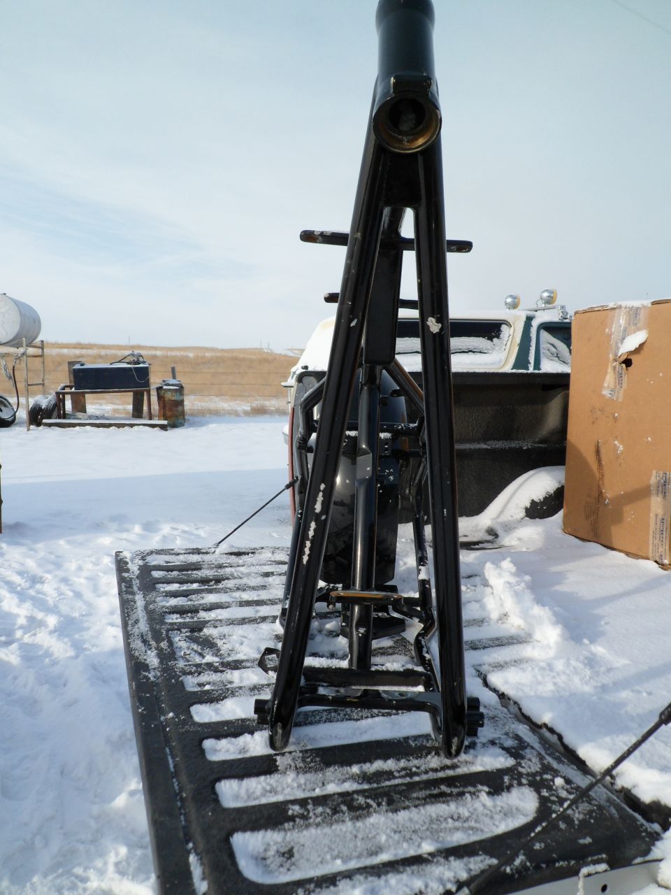 Black motorcycle frame on a pickup truck bed in the snow