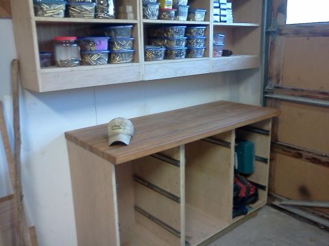 1996 Ford Bronco - A workbench with organized shelves above, holding ammunition and other supplies, with a baseball cap resting on the surface.