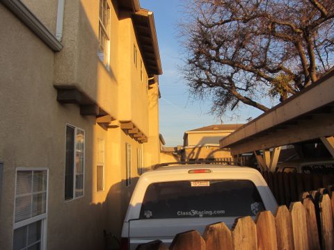 1968 Ford Mustang - A white SUV is parked next to a building, partially covered by a carport.