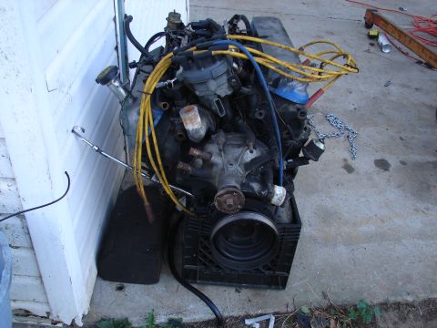 1973 Ford Ranchero - Engine assembly with yellow spark plug wires sits on a black plastic crate.