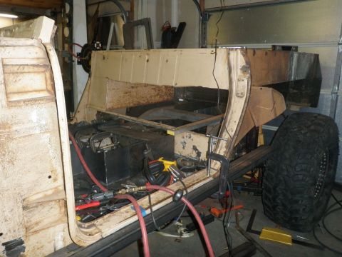 1961 International Scout 800 - This vehicle chassis is undergoing extensive modification and repair, with tools and equipment visible around the frame.