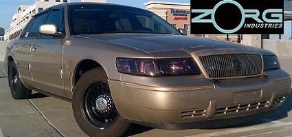 2000 Mercury Grand Marquis - Gold 2000 Mercury Grand Marquis sedan with dark tinted headlights and black steel wheels is parked on a rooftop.