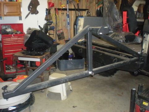 1978 Ford Bronco - A custom-built spare tire carrier is shown mounted in a garage setting, with tools and equipment visible in the background.