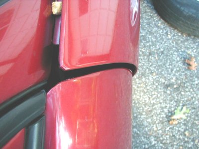 1997 Ford Taurus - The gap between the car door and body panel is visible, along with a portion of a tire and some fallen leaves.