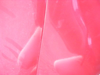 1997 Ford Taurus - Close-up of a pink car's body panel seam shows damage and a watermark.