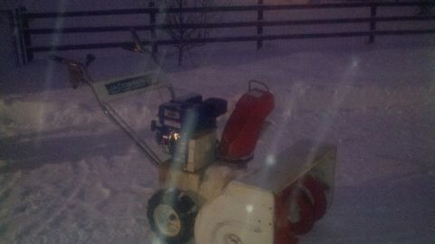 1978 Ford Mustang II - A snow blower sits in the snow with a wooden fence in the background.