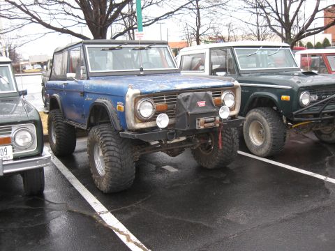 1994 Ford Bronco - A blue 1973 Ford Bronco is parked next to other Broncos at a meet and greet event.