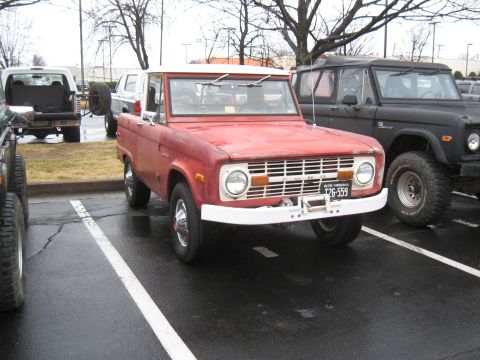 1994 Ford Bronco - A red first-generation Ford Bronco is parked in a lot next to a black Bronco.