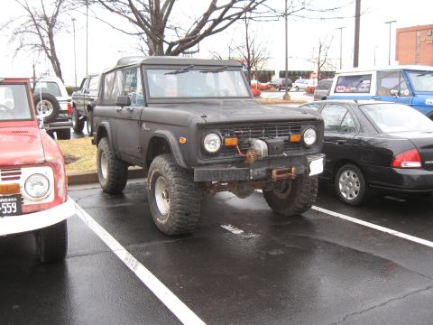 1994 Ford Bronco - A black Ford Bronco is parked in a lot next to other vehicles.